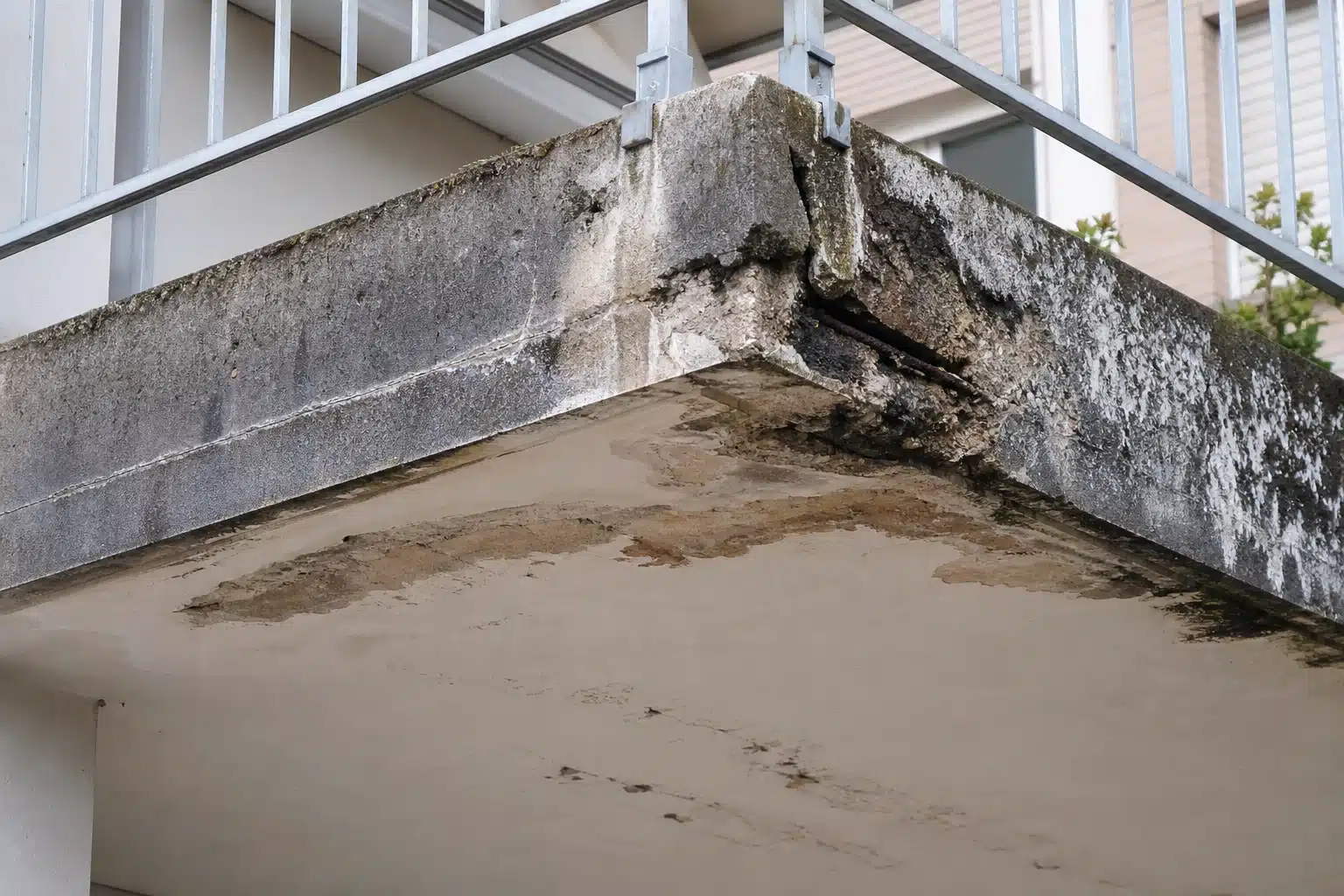 Coin de balcon en béton effrité avec traces d'humidité